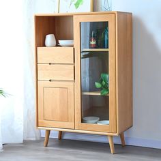 a wooden cabinet with glass doors on the top and bottom, next to a potted plant