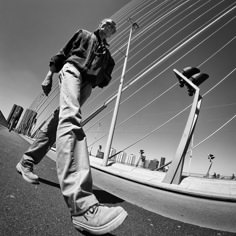 a man riding a skateboard down the side of a road next to tall poles