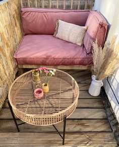 a couch sitting on top of a wooden floor next to a table with two vases