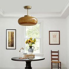 a room with a table, chairs and pictures on the wall above it that has sunflowers in a vase