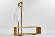 a clothes rack with a white shirt hanging on it's hanger and a wooden shelf