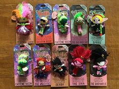 several small troll dolls are in their packagings on the wooden table with tags attached to them