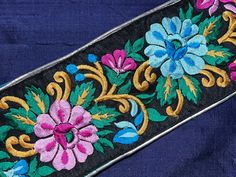 an embroidered belt with flowers and leaves on black velvet fabric, close up view from the bottom