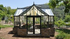 a small glass house sitting on top of a dirt field