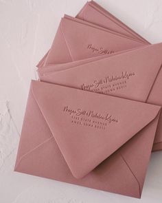 four pink envelopes are stacked on top of each other, with the same address printed on them