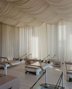 an empty room with white drapes on the ceiling and chairs lined up in rows