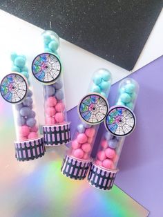 three clear tubes filled with candy on top of a rainbow colored table next to a black and white sign