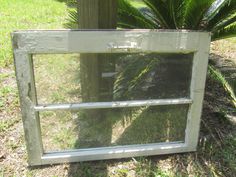 an old window sitting in the grass next to a tree