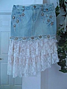 a skirt made out of old jeans with lace and beaded trims hanging on a wall