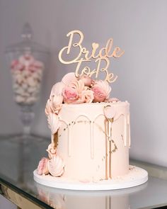 a wedding cake decorated with pink flowers and gold lettering