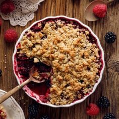 a bowl filled with berries and crumbs next to another bowl full of raspberries