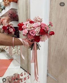 a person holding a bouquet of flowers in front of a door with pink ribbons on it