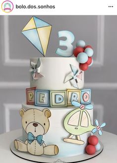 a three tiered birthday cake decorated with teddy bears and kites on the top