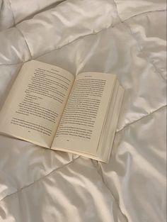 an open book laying on top of a bed