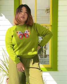 Woman wearing green long sleeved sweater with butterfly on the front Colorful Winter Fashion, Snazzy Outfits, Knit Butterfly, Funky Fits, Color Characters, Cartoon Sweater, 1980s Aesthetic, Cute Winter Sweaters, Sweaters Outfit