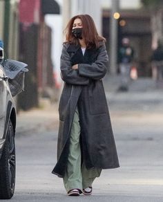 a woman is walking down the street talking on her cell phone while wearing a face mask