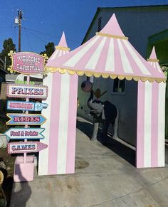 a pink and white circus tent sitting next to a sign