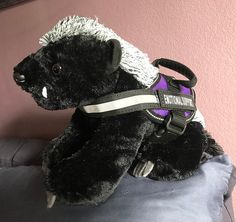 a stuffed animal that is wearing a harness on it's back sitting on a pillow