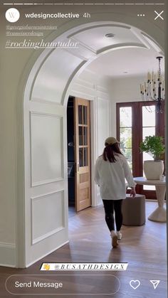 a woman is walking through an archway in a house with white walls and wood floors