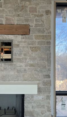 a fire place in the middle of a room with a brick wall and window above it