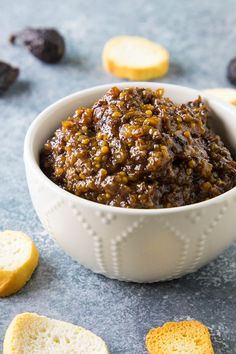 a white bowl filled with food next to crackers and raisins on a table