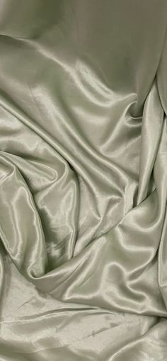 a close up view of a light green satin fabric with very soft folds and wrinkles