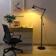 a desk with a chair, lamp and pictures on the wall in front of it