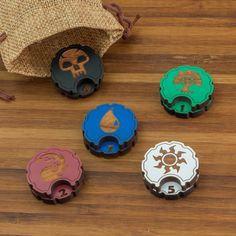 four different colored bottle openers sitting on top of a wooden table next to a bag