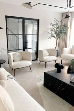 a living room filled with white furniture and a black coffee table in front of a window