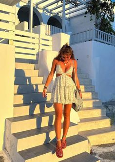 a woman is walking down some stairs with her hand on her hip and wearing sandals