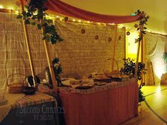 a table with food on it in front of a wall decorated with lights and greenery