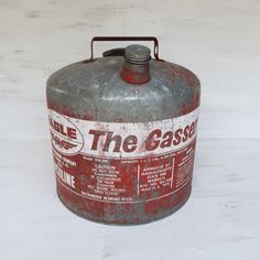 an old gas can with the words the gasser on it sitting on a white surface