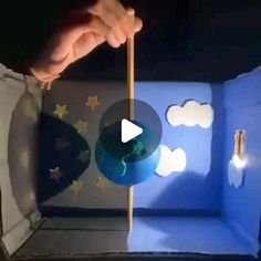 a person holding a stick in front of a blue box with clouds and stars on it