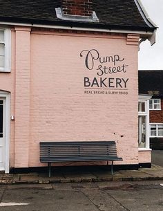 a pink building with a bench in front of it on the side of the road