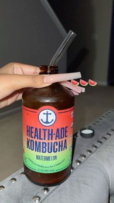 a person holding a toothbrush next to a jar of kombucha