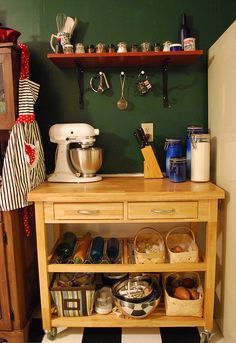 a kitchen with green walls and lots of clutter on the shelf next to it