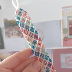 a hand holding a piece of beaded material in the shape of a cross - stitch