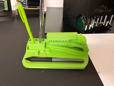 a green pen holder with two pens and a pencil in it sitting on a table