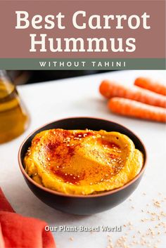 a bowl filled with hummus next to carrots