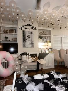 balloons are hanging from the ceiling in a room with white furniture and black table cloths