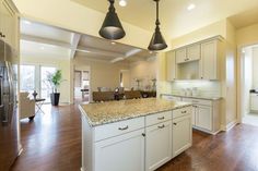 a large kitchen with white cabinets and granite counter tops, along with an island in the middle