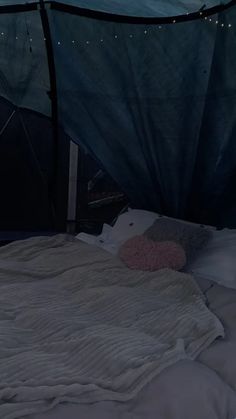 an unmade bed in a tent with lights on the ceiling and sheets pulled down