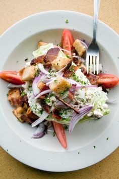 a white plate topped with salad next to a fork