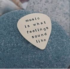 a guitar pick with the words music is what feelings sound like on it sitting on top of a rock