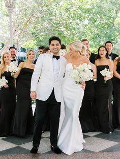 a bride and groom standing in front of their wedding party