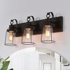 three light bathroom fixture with clear glass and metal caged lights on the wall above it