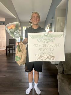 a man holding a sign that says messing around paid to go to college and flowers