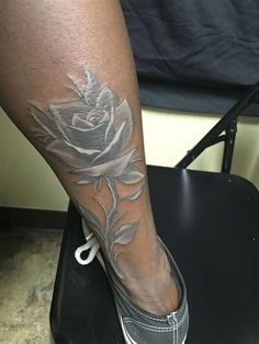 a woman's leg with a rose tattoo on it, sitting on a chair