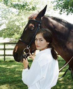 a woman standing next to a brown horse