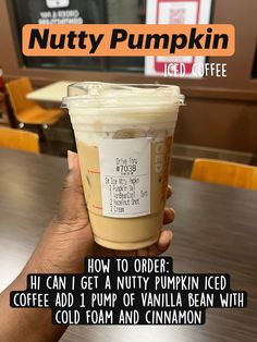 a person holding up a cup of nutty pumpkin iced coffee